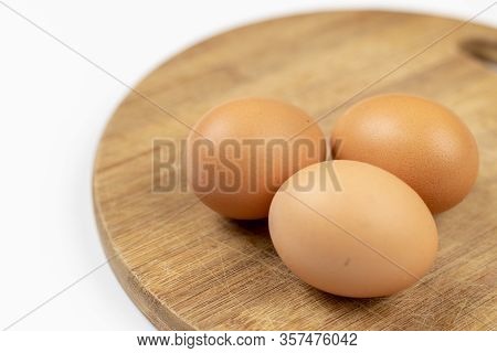 Three Chicken Eggs Isolated Above Roung Wooden Board