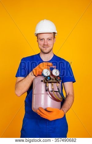 A Male Air Conditioning Repairman Is Holding A Freon Cylinder In His Hands To Air-condition The Air 