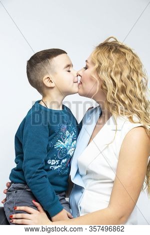 Portrait Of Kissing Caucasian Mother With Her Son In Studio Indoors. Posing Against White Background