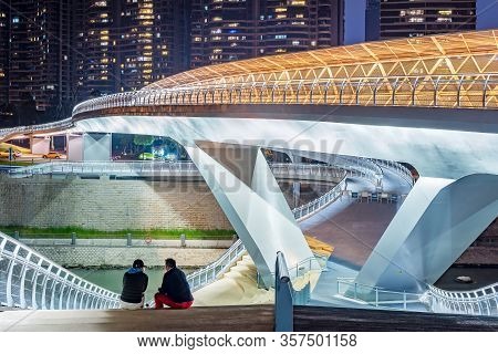 Chengdu, Sichuan Province, China - March 12, 2020 : Two People Sitting On A Modern Bridge Illuminate