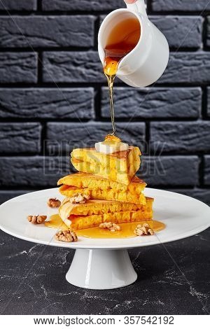 Woman Pouring Honey Or Syrup On A Stack Of Slices Of Sponge Pancake Topped With Butter And Walnuts
