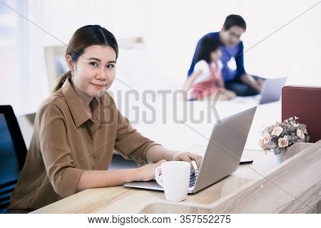 Asian Businesswoman Mother Working At Home With Notebook Computer, Tablet, And Smartphone While Her 