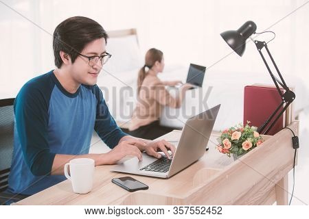 Asian Businessman Using Notebook Computer Working From Home While His Businesswoman Wife Doing Her W