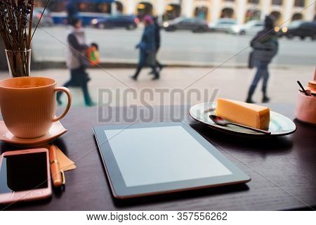 Modern Touch Pad Lying On A Wooden Table In Coffee Shop Near Mobile Phone And Cup Of Latte. Digital 