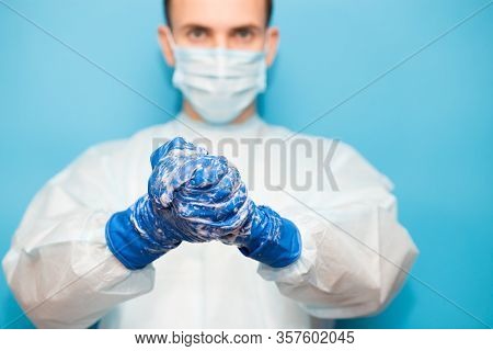 Doctor In Medical Suit Protective Mask And Gloves Washing Hands Before Operating Isolated On Blue Ba