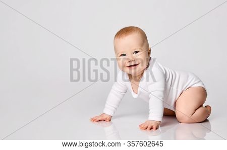 Chubby Ginger Baby Boy In Bodysuit, Barefoot. He Smiling, Creeping On Floor Isolated On White Studio