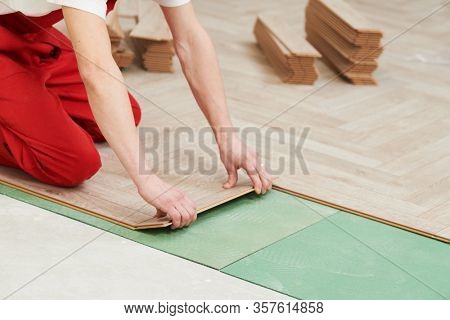 worker laying laminate floor covering at home renovation