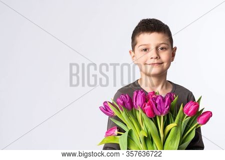 Confident Little Boy Holds Rpink Tulips In His Hands And Looking At The Camera, Isolated Over White 