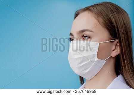 Doctor Nurse Smiling Behind Surgeon Mask. Closeup Portrait Of Young Caucasian Woman Model On Blue Ba