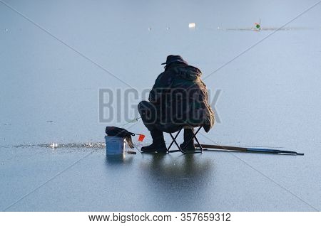 Fisherman On A Frozen Lake In A City Park. Kalush, Ukraine (grainy Texture Of Ice.)