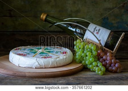 Cheese Brie With Bottle Of Chardonnay Of Casillero Del Diablo With Bunch Of Grapes On The Table