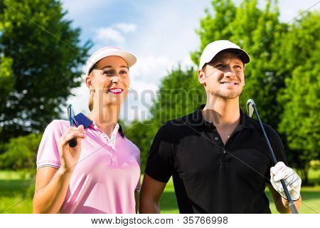 Young sportive couple playing golf on a golf course, they certainly do exercise or have training