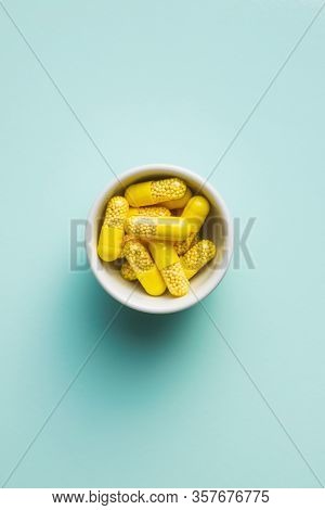 Vitamin capsules. Vitamin C pills in bowl on colorful background. Top view.
