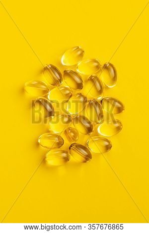 Omega 3 pills. Fish oil supplement capsules on yellow background. Top view.