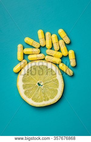 Vitamin capsules. Vitamin C pills and slice of lemon on colorful background. Top view.