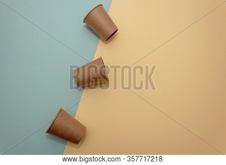Three Craft Paper Cups For Coffee Or Any Drinks On A Blue And Yellow Paper Background. Concept Of Zi