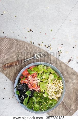 Salted Salmon Poke Bowl With Avocado, Sea Cale, Cucumber, Sesame Seeds And Bean Sprouts On Grey Back