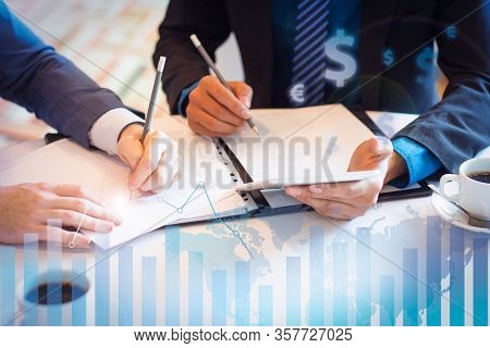 Partners Working With Documents With Financial Analysis Graphs. Cropped View Of Two Businessmen Sitt