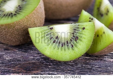 Sliced Into Halves And Pieces Fresh Sour Or Sweet Green Kiwi Fruit On A Wooden Table, Making A Fruit