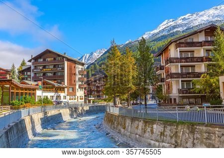 Zermatt, Switzerland - October 7, 2019: Town Street View In Famous Swiss Alps Ski Resort, River, Sno