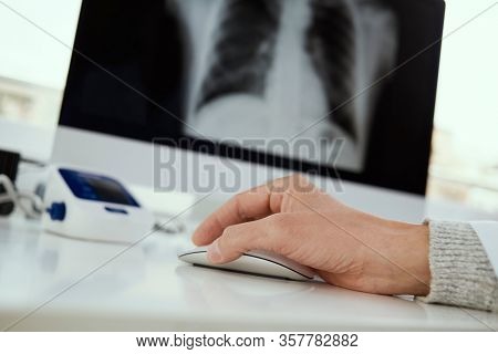 closeup of a young doctor man sitting at his desk checking a chest radiograph in his computer