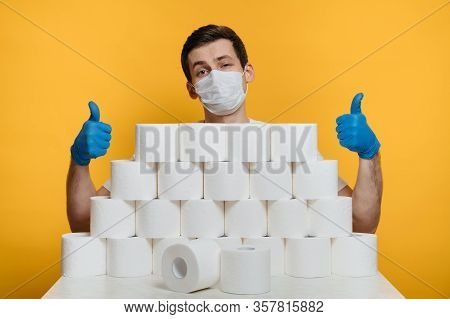 Selfconfident And Happy Young Man In Protective Face Mask And Medical Gloves Behind The Stack Of Toi