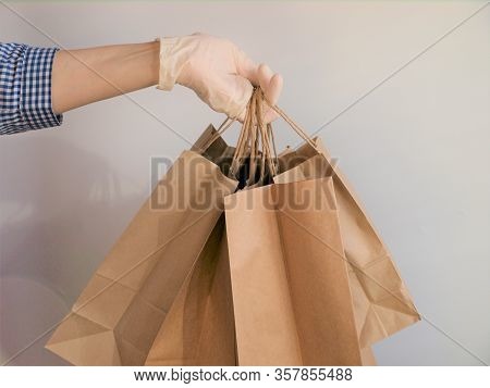 Courier In A Checkered Blue Shirt With Medical Latex Gloves Safely Delivers Online Purchases In Brow
