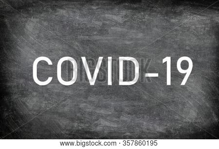 COVID-19 white chalck text on blackboard chalkboard texture distressed grunge background. Graphic design of corona virus drawing with title.