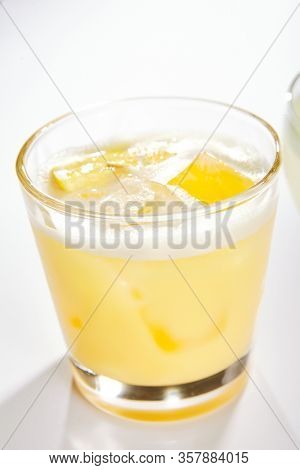 Lemon pie cocktail close up. Alcohol strong drink in glass side view. Beverage with vodka and lemon juice in drinkware. Cocktail portion with crushed ice and vanilla flavor in glassware