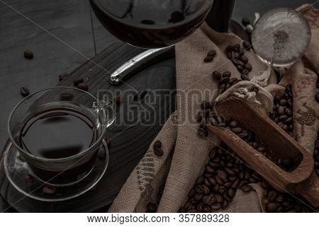 Coffee Style, Cup Of Coffee And Coffee Beans Roating With Old Wooden Scoop And Coffee Beans Around O