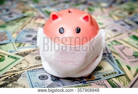 Piggy Bank In A Mask On A Background Of American Currency.the Concept Of Coronavrius Epidemic