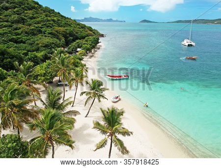 Aerial view of Petit Rameau tropical Caribbean Island beach, sailing catamarans and boats from above 