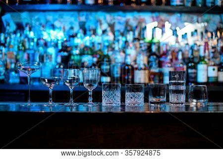 Several Glasses Of Different Forms Stand On Bar Counter.