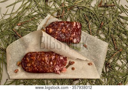 Dried Sausage Made Of Beaver Meat On Parchment With Pine Buds At The Bottom. Flooring Made Of Pine N