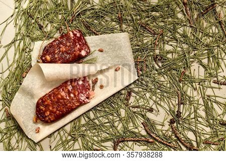 Dried Sausage Made Of Beaver Meat Cut With Slices On Parchment With Pine Buds On The Left Flooring M