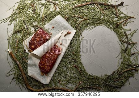Dried Sausage From Beaver Meat On Parchment Paper And An Empty Frame From Needles. Composition In A 