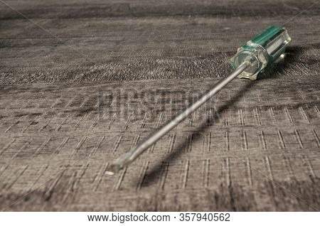 Shiny Screwdriver With A Flat Sting And A Transparent Handle On The Desktop