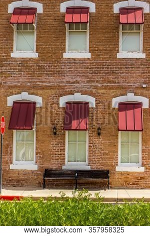 Lone Wooden Bench Under Six Windows And Canopies