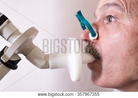 Senior Hispanic Man Man Testing Breathing Function By Spirometry.