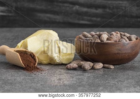 Cocoa Butter Or Cocoa Bean Solid Oil With Cacao Powder In Spoon Or Bowl And Raw Cocoa Beans On Rusti