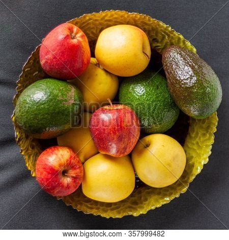 Colorful Fruits On Glass Plate On Black Background. Top View. Red And Yellow Apples With Some Avocad