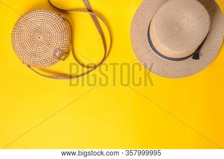 Straw Beach Hat And Woven Rattan Bag On A Yellow Background