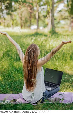 The Girl Sits Outdoors And Works At A Laptop. She Rejoices At The End Of The Working Day. Freelance.