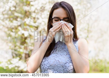 Beautiful Caucasian Young Girl Against Blooming Spring Trees Poses With White Napkin, Has Bad Case O