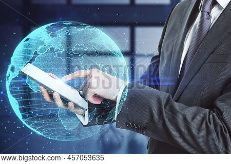 Close Up Of Workplace With Laptop And Creative Glowing Polygonal Grid Planet On Blurry Office Interi