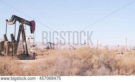 Wells With Pump Jacks On Oil Field, California Usa. Rigs For Crude Fossil Extraction Working On Oilf