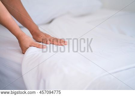 Female Hand Set Up White Bed Sheet In Bedroom Or Maid Hands Making Bed In A Hotel Room.