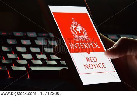Person Holding Smartphone With Interpol Logo Displayed On Screen.