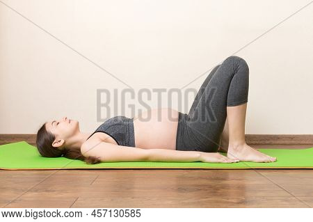 Beautiful Young Pregnant Woman Sitting On Mat In Yoga Pose At The Home. Pregnancy Yoga And Fitness C