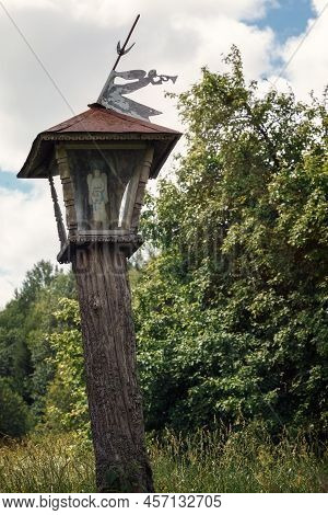 Lithuania, Plateliai, Wooden Carved Chapel Pillar With Trumpet Angel On Top Near The Ethnographic Ho